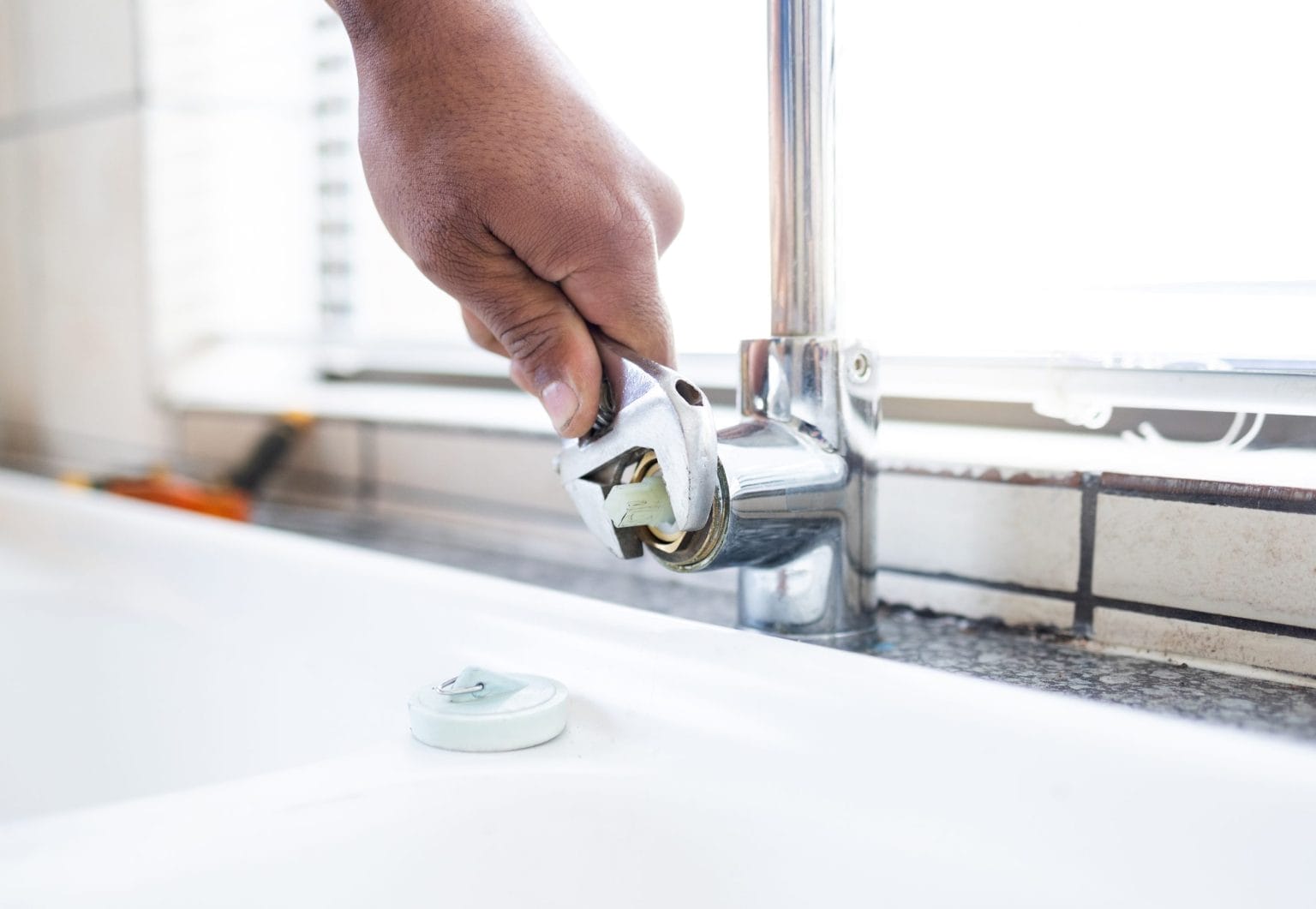 Plumber using wrench for sink leak repairs
